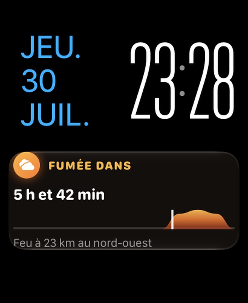 Apple Watch affichant l'activité Firewatch sous le cadran : « Fumée dans 5 h et 42 min », feu à 23 km au nord-ouest, avec la vague de fumée en bandeau
